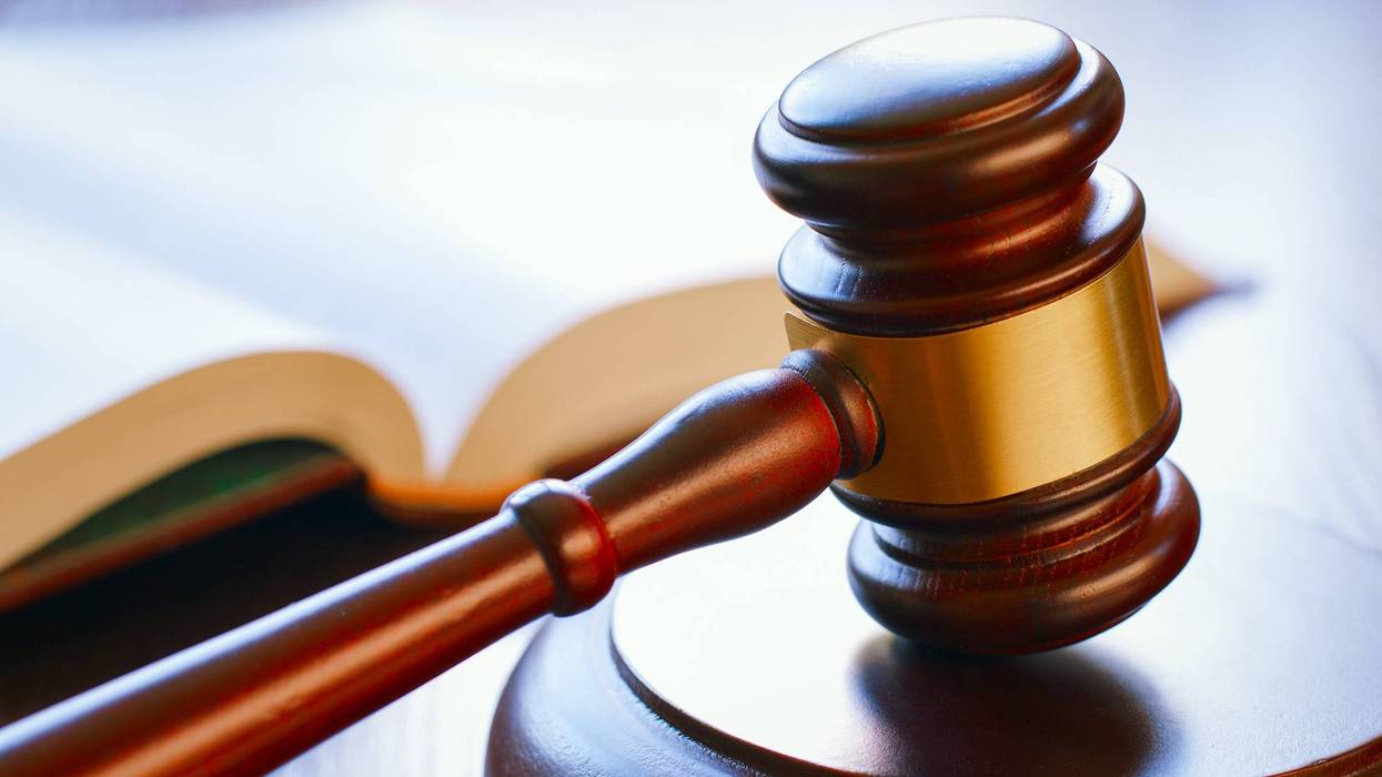 brown gavel and open book on a wooden table of the law in the courtroom