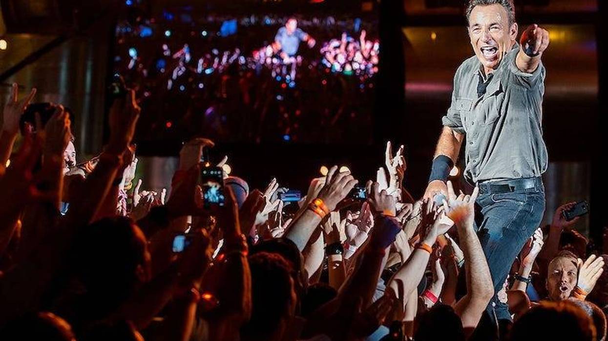 Bruce Springsteen performing in concert interacting with fans.