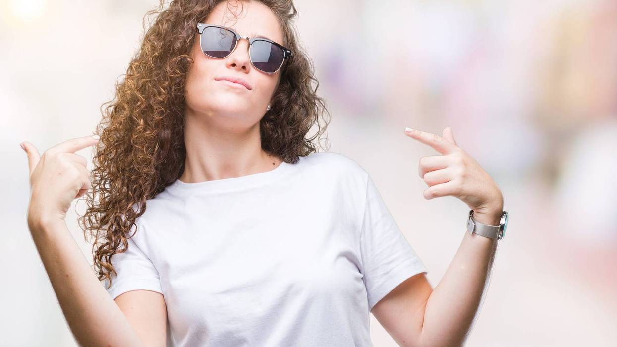 brunette curly hair young girl wearing sunglasses over isolated background looking confident with smile on face, pointing oneself with fingers proud and happy