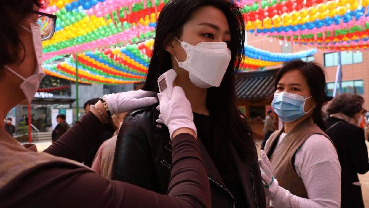 Buddhist believers wear masks as a preventive measure against the coronavirus (COVID-19), receive body temperature check as they arrive to attend a birthday of Buddha ceremony and service to pray for overcoming the coronavirus (COVID-19) pandemic at Jogyesa Temple on April 30, 2020 in Seoul, South Korea.