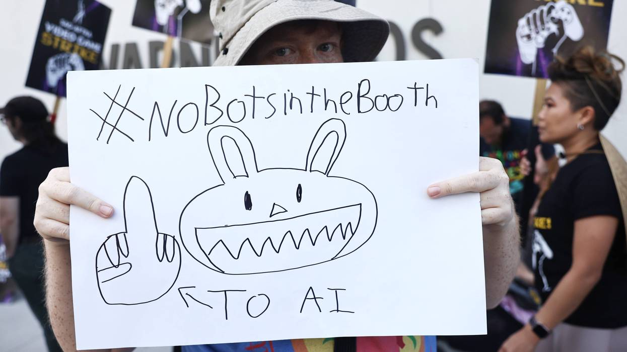 BURBANK, CALIFORNIA - AUGUST 28: A picketer carries a sign referencing bots as striking SAG-AFTRA video game performers picket outside WB Games Inc. offices on August 28, 2024 in Burbank, California. The Hollywood walkout involving video game voice actors along with motion-capture performers began July 23rd with negotiations primarily over AI (Artificial Intelligence) protections for the workers.