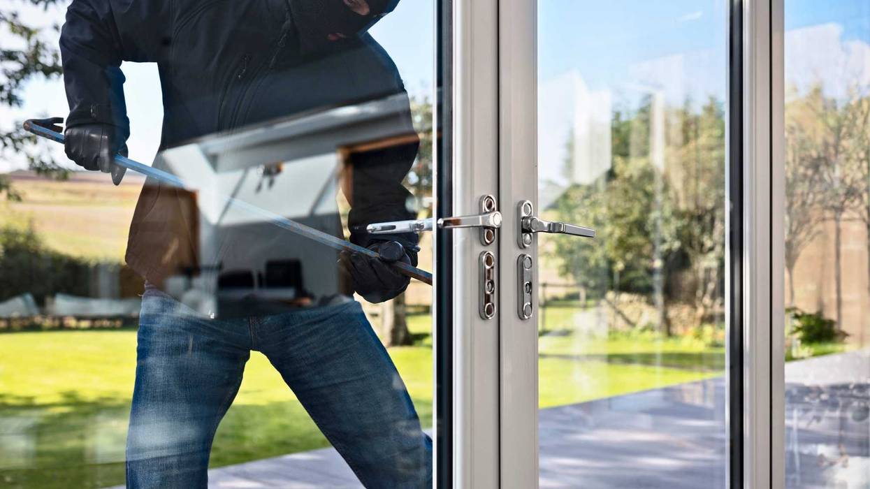 Burglar trying to enter a house by breaking through glass doors.