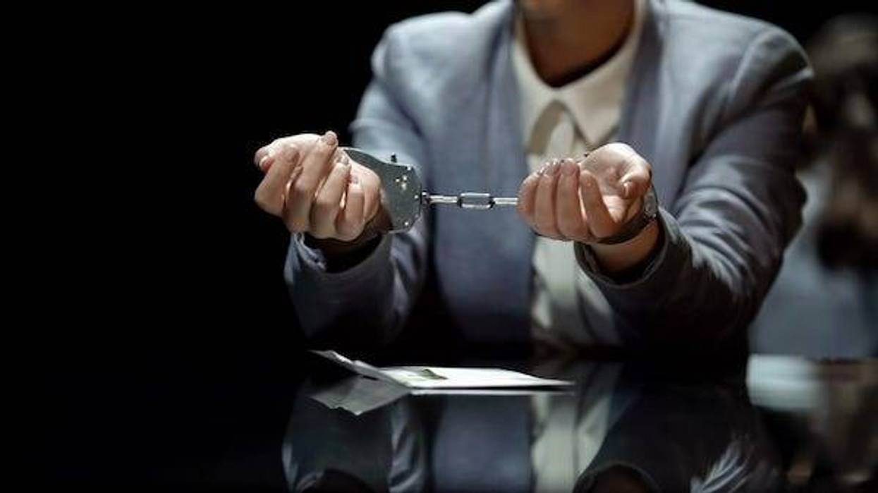 Business woman in suit wearing handcuffs