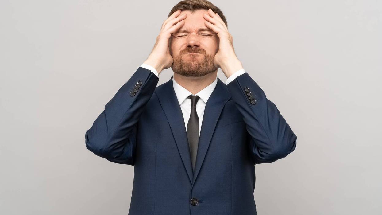 Businessman touching head with frown disappointed sickly emotional face isolated studio background.