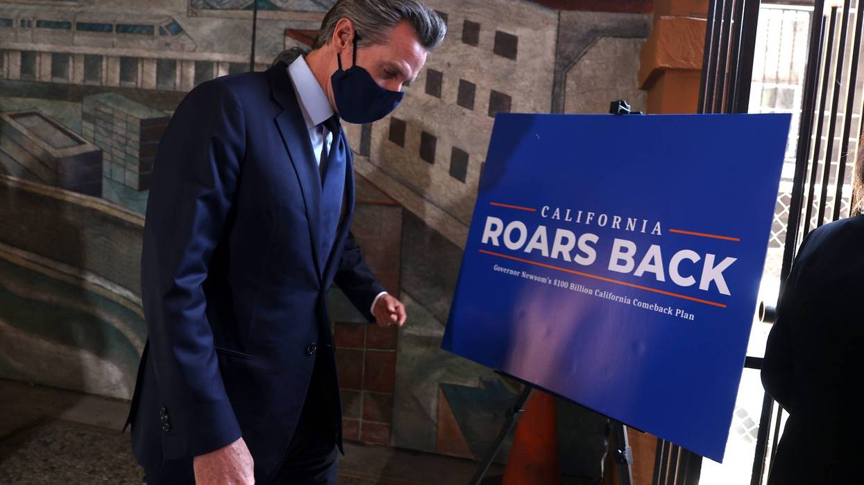 California Gov. Gavin Newsom walks by a sign as he leaves a press conference at The Unity Council on May 10, 2021 in Oakland, California.