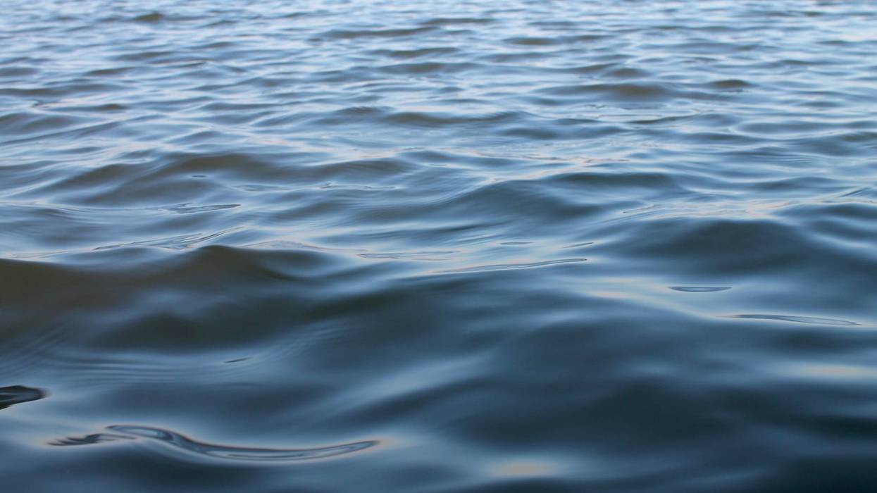 Calm shiny waves at sunset light on a lake surface