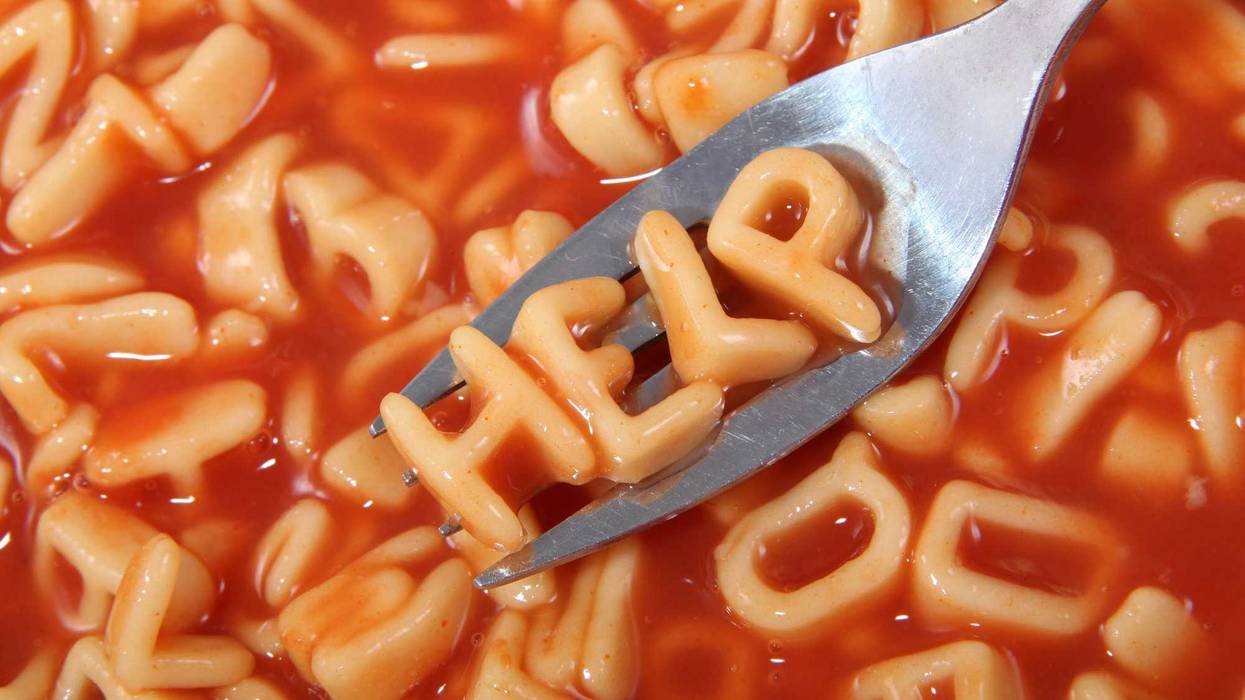 Canned spaghetti noodles spelling out the word "help" on a utensil.