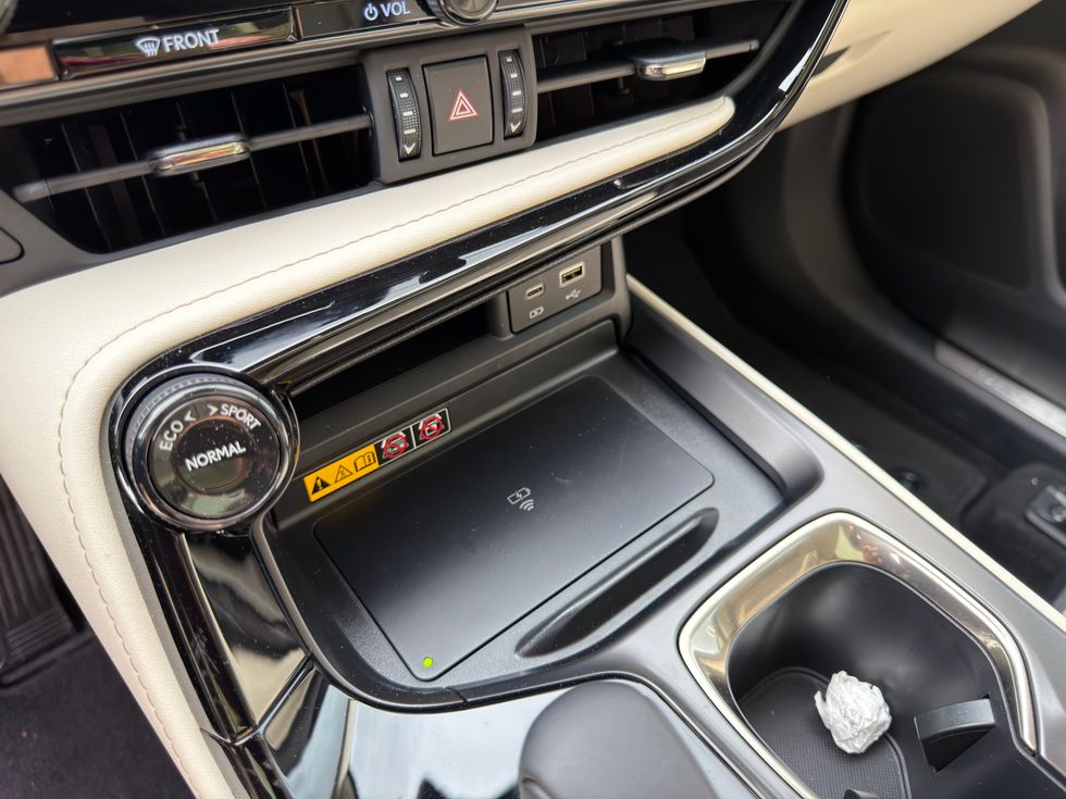 Car interior showing drive mode selector, wireless charging pad with green light, and USB ports.
