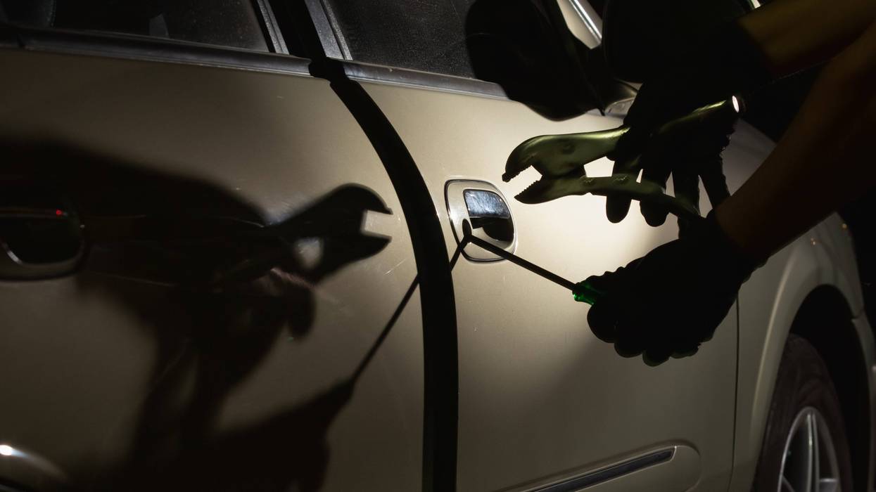 Car thief using a tool to break into a car