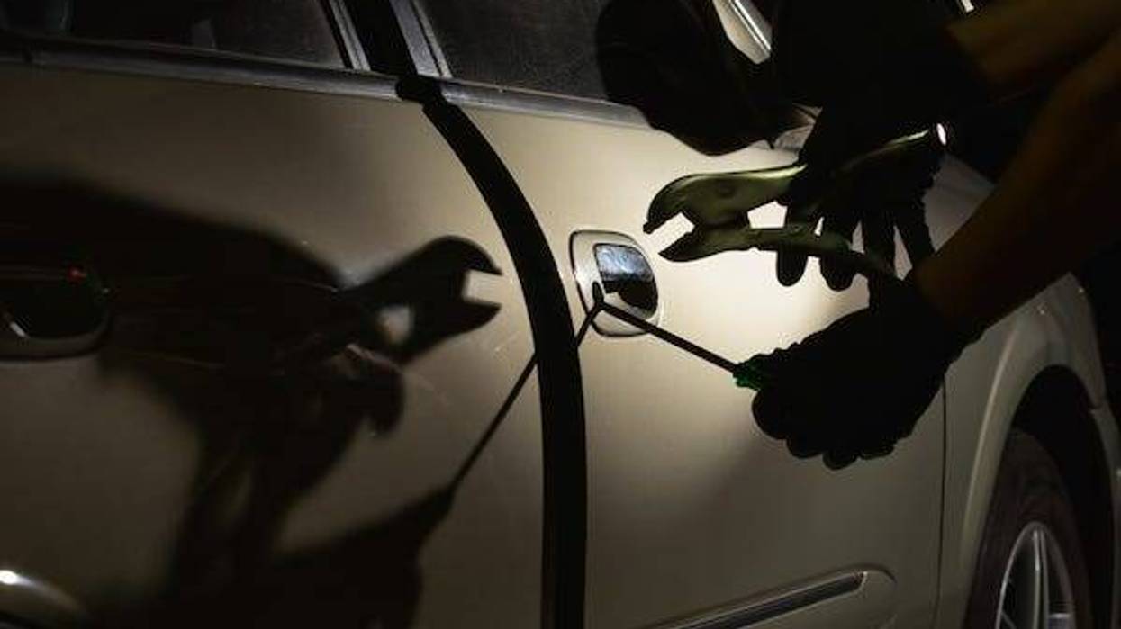 Car thief using a tool to break into a car