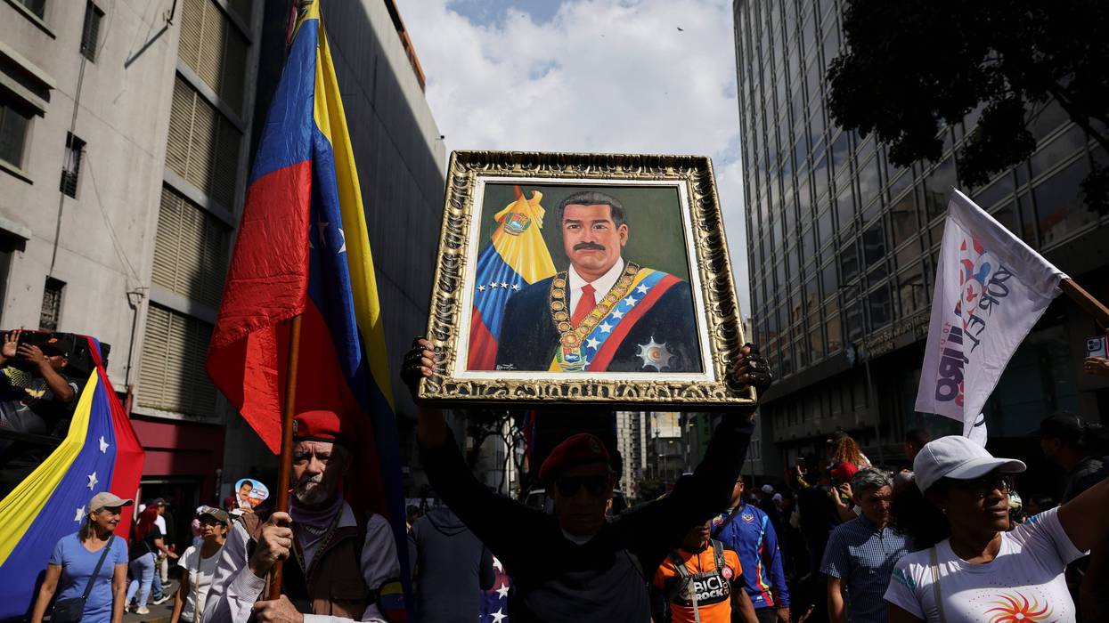 CARACAS, VENEZUELA - JANUARY 6: A man holds a portrait of Nicolas Maduro during a march in his support and his wife Cilia Flores after their capture by U.S. forces, on January 6, 2026 in Caracas, Venezuela. U.S. President Donald Trump announced on January 3 that his country's military had launched a large-scale attack on Venezuela and captured its President Nicolas Maduro, and his wife, Cilia Flores. As citizens start to struggle with the lack of supplies and water, the National Assembly has appointed Vice President Delcy Rodriguez as Acting President. (Photo by Jesus Vargas/Getty Images)