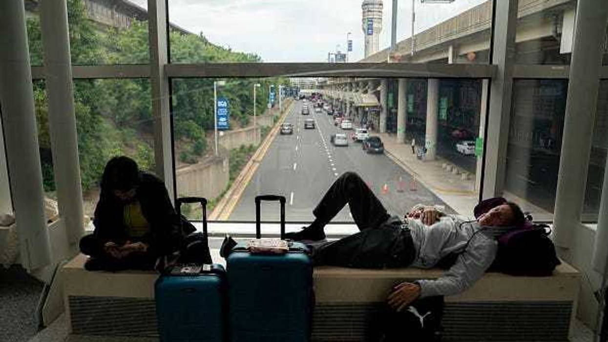 Carl Salazar (right) sleeps at Ronald Regan Washington National Airport while waiting for a delayed United flight on July 19, 2024 in Washington, DC. A global computer outage started from an update from the cybersecurity company CrowdStrike impacted flights worldwide along with disrupting broadcasters and banking services. (Photo by Nathan Howard/Getty Images)