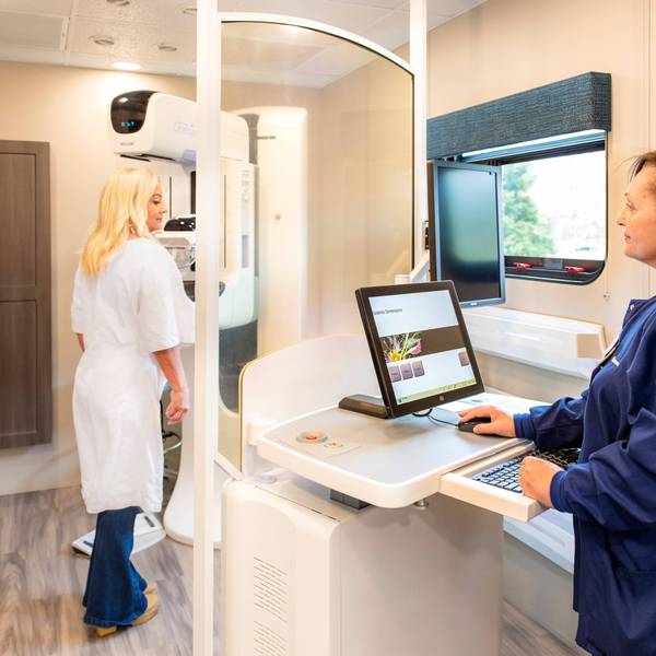 Carmen Aviles (right) demonstrates a mammogram on Virtua Health's mobile cancer screening bus.