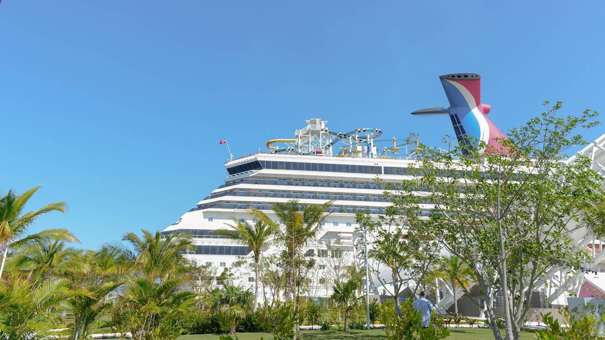 Carnival cruise ship docked in tropical paradise with palm trees and clear blue sky in the background