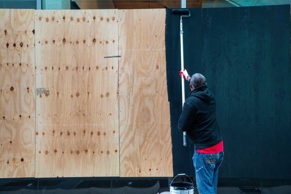 Carpenters board up and paint the windows to an American Eagle store in Times Square on November 1, 2020 in New York City.