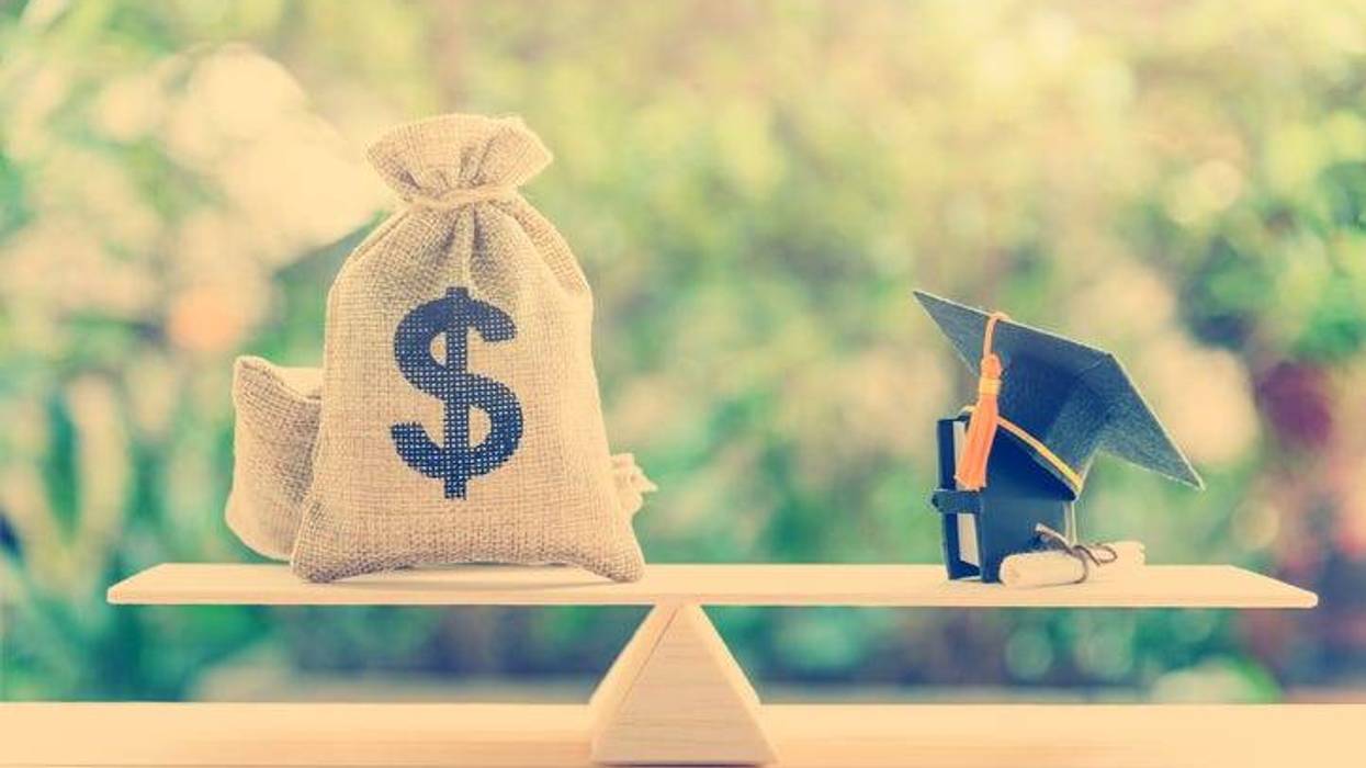 cash in hessian bags, a black graduation cap or hat, a certificate / diploma and a book on simple balance scale