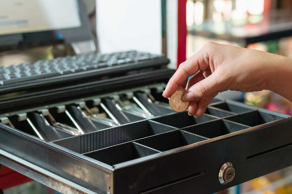 Cashier putting money in a cash register.