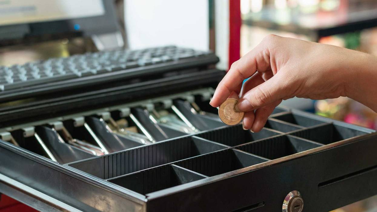 Cashier putting money in a cash register.
