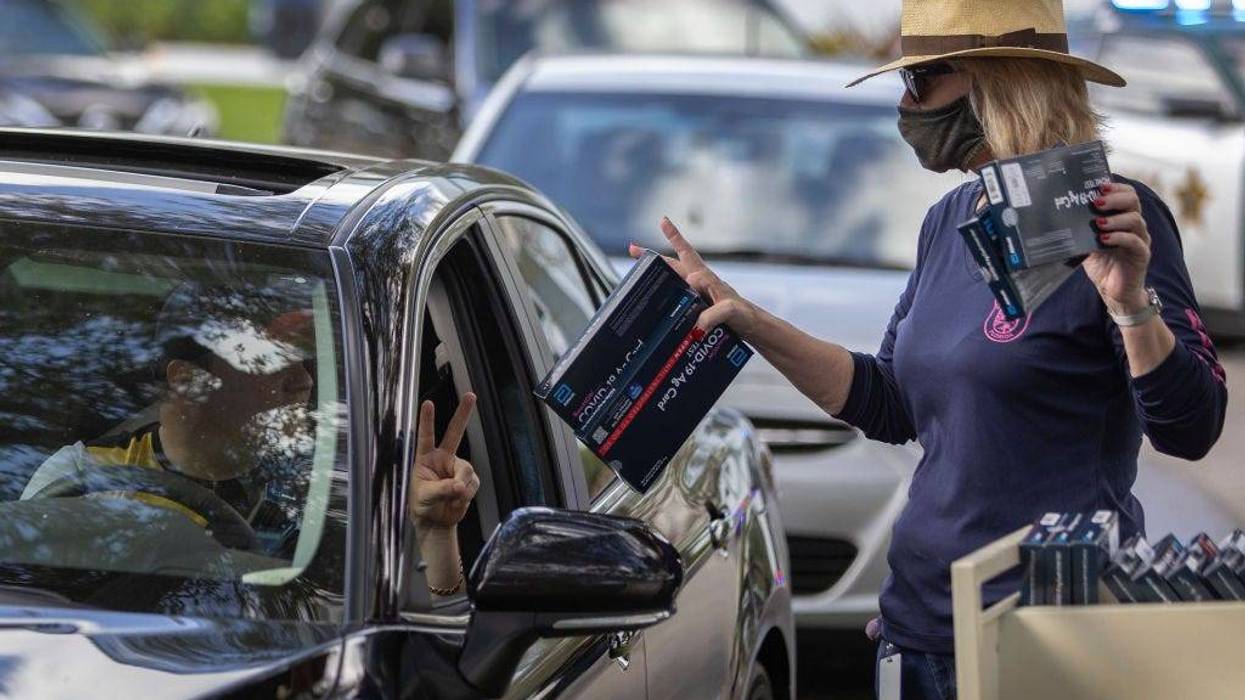 Cathy Feller hands out free COVID-19 at-home rapid test kits during a drive-thru event at the Hollywood library on December 30, 2021 in Hollywood, Florida.