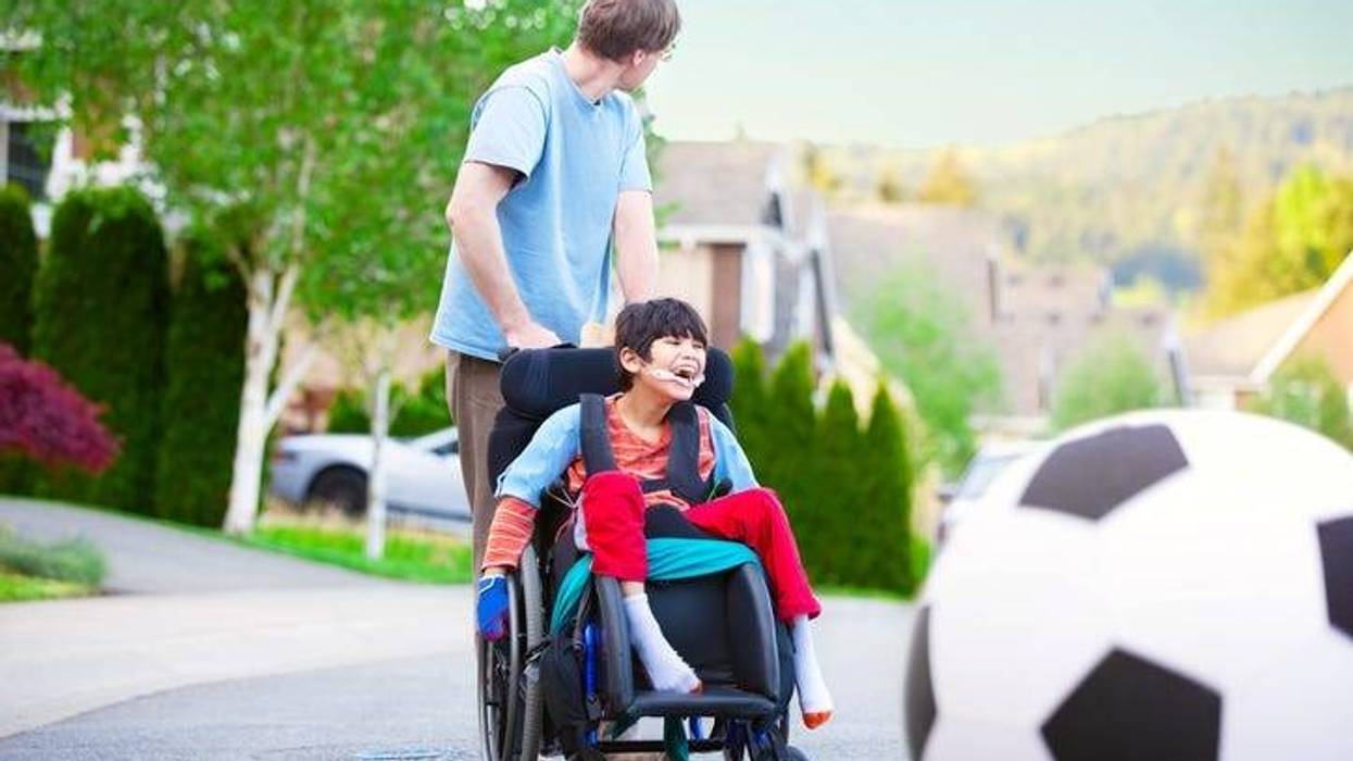 Caucasian father helping disabled son in wheelchair play soccer