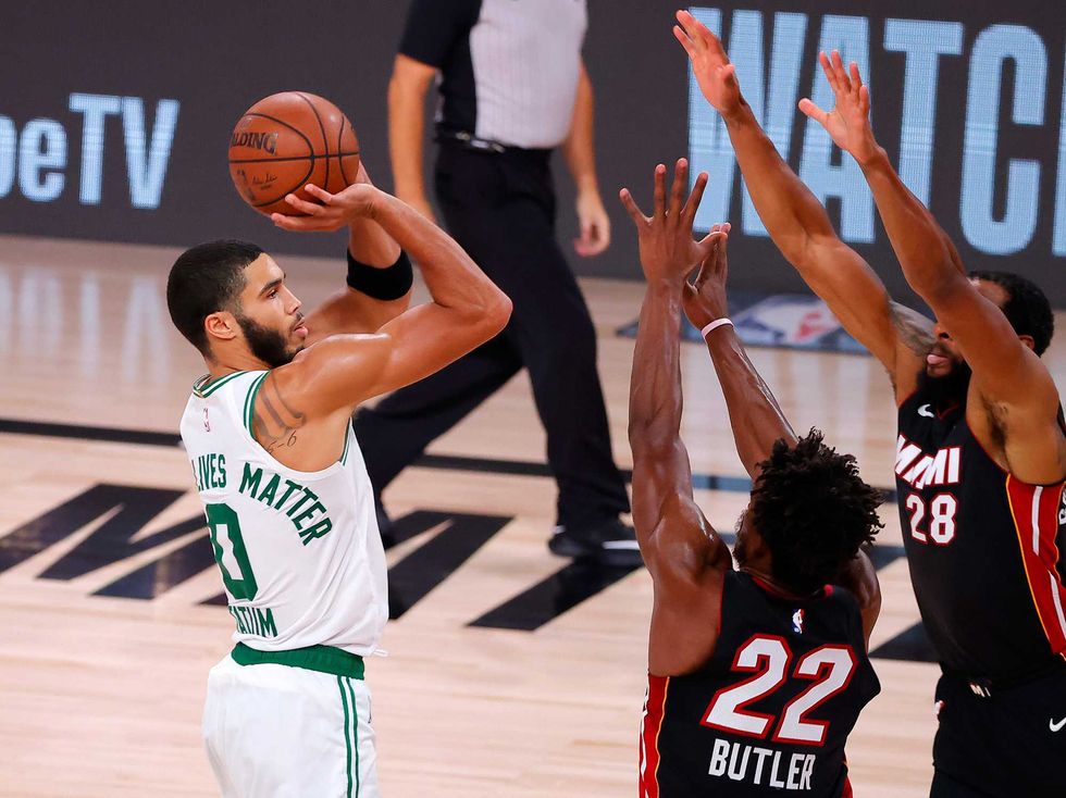 Celtics forward Jayson Tatum attempts a shot against Heat defenders Jimmy Butler and Andre Iguodala