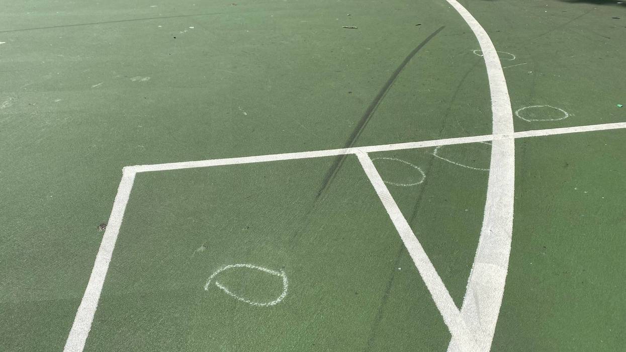Chalk outlines, showing where bullet casings were found, remained on the playground athletic courts.