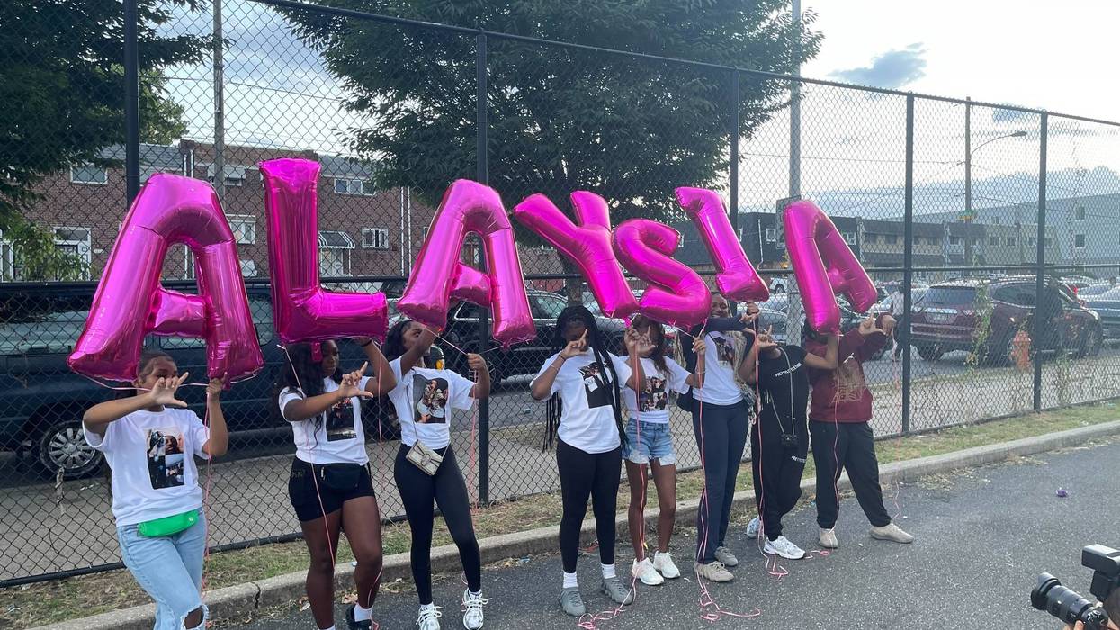 Cheer teammates of Alaysia Smith holding balloons spelling out her name.