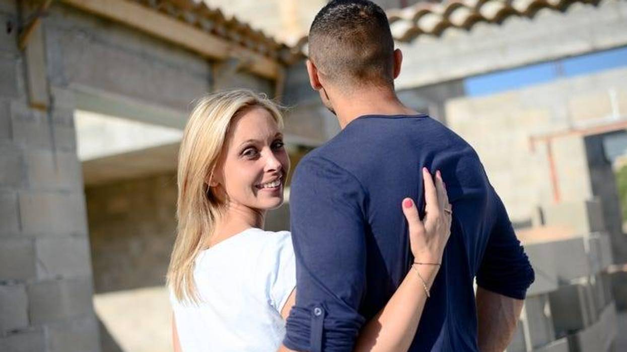 cheerful young happy couple in love in front of contruction site of their new house