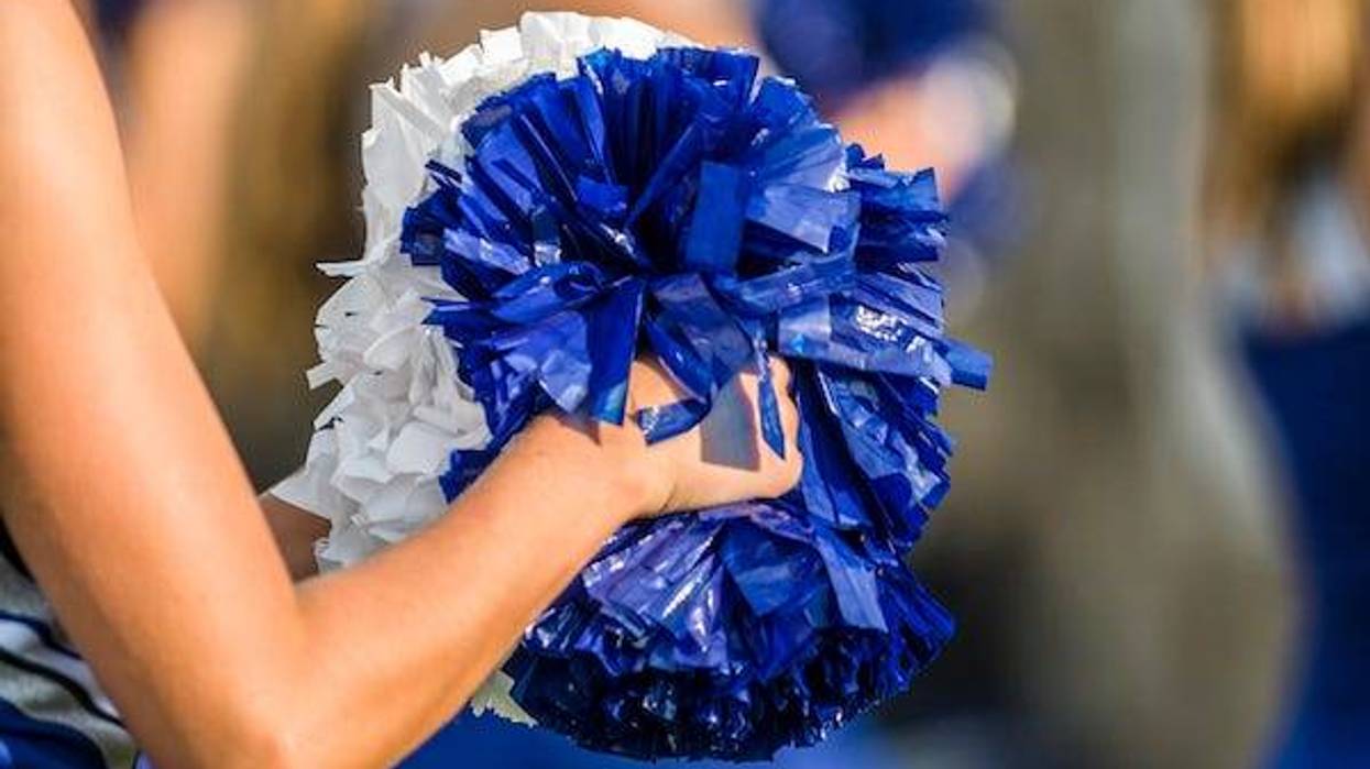 Cheerleader shaking blue and white pom poms
