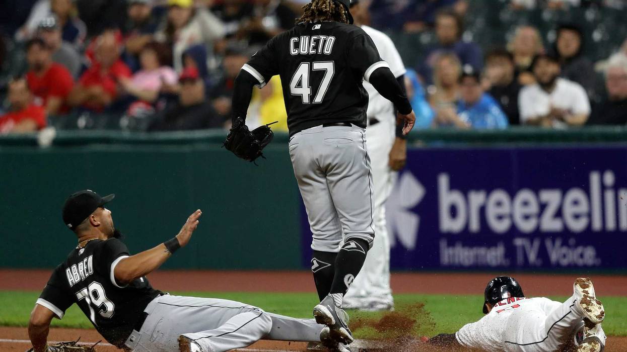 Chicago White Sox first baseman Jose Abreu (79) slides to first base to force out Cleveland Guardians Andres Gimenez (0) as pitcher Johnny Cueto jumps out of the way in the second inning at Progressive Field.