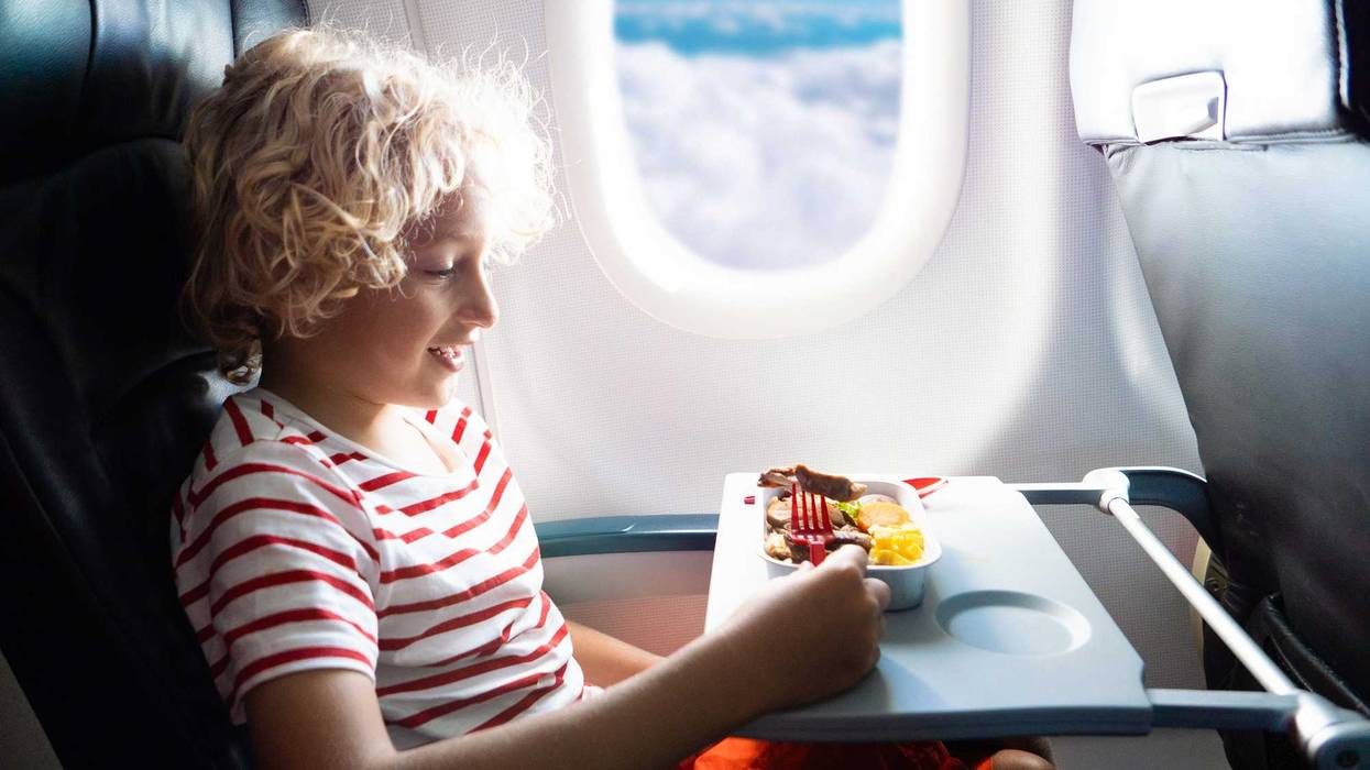 Child eating a meal on a plane.
