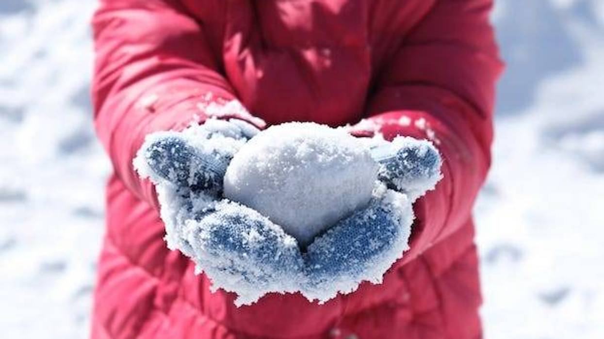 Child holding snowball in mittens