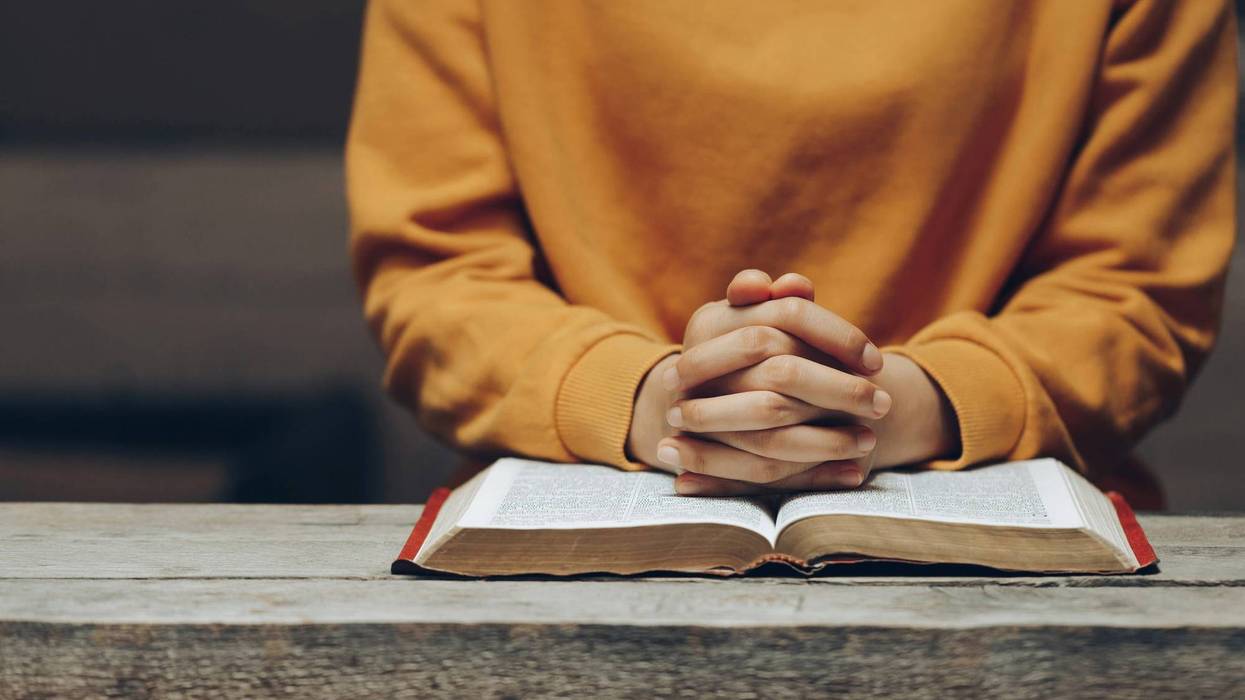 Child praying on a book on a desk