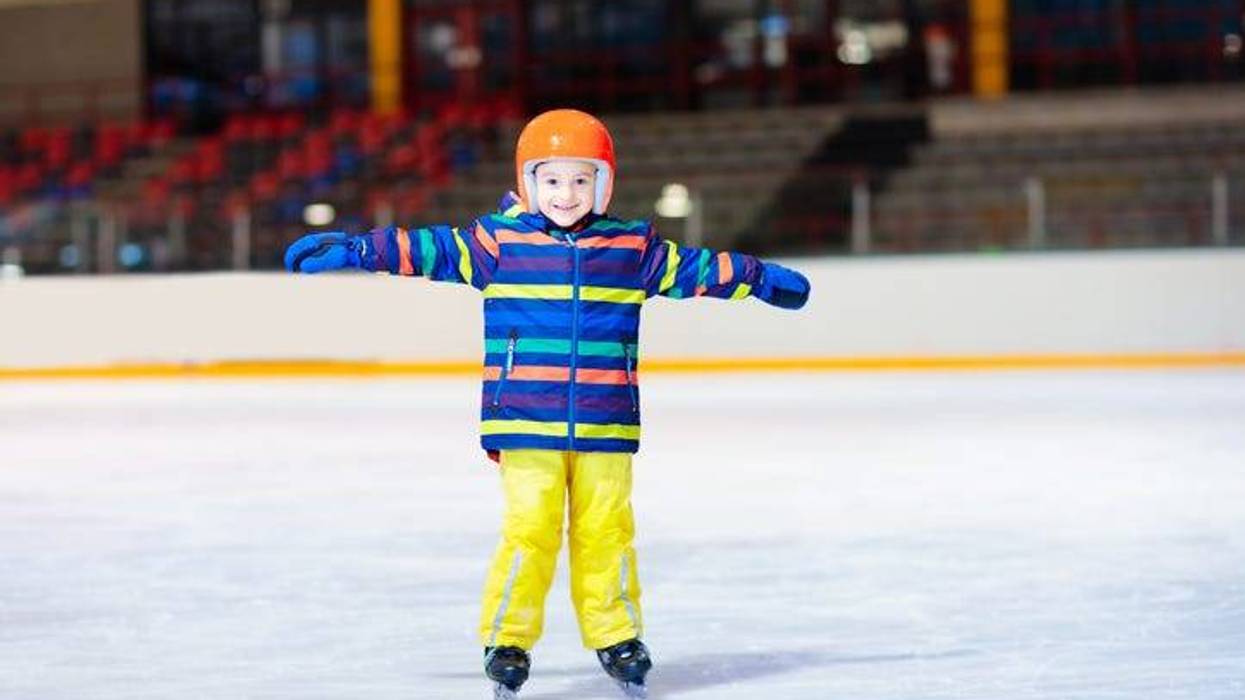 Child skating on indoor ice rink. Kids skate. Active family sport during winter vacation and cold season. Little boy in colorful wear training or learning ice skating. School sport activity and clubs