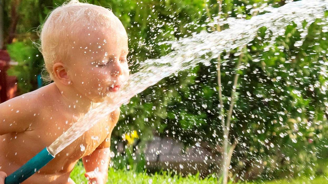 Child watering the grass in the yard