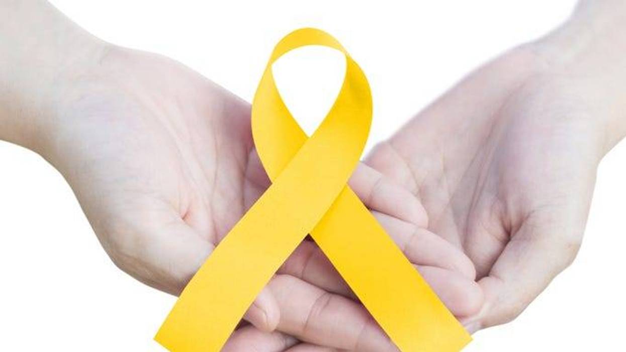 childhood cancer awareness gold ribbon on hands isolated on white background