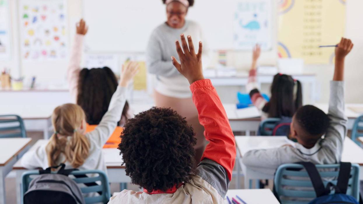 Children, back and hands raised at school for question, answer and learning at youth academy. Kids, education and teacher for development with sign for talking, quiz and scholarship in classroom