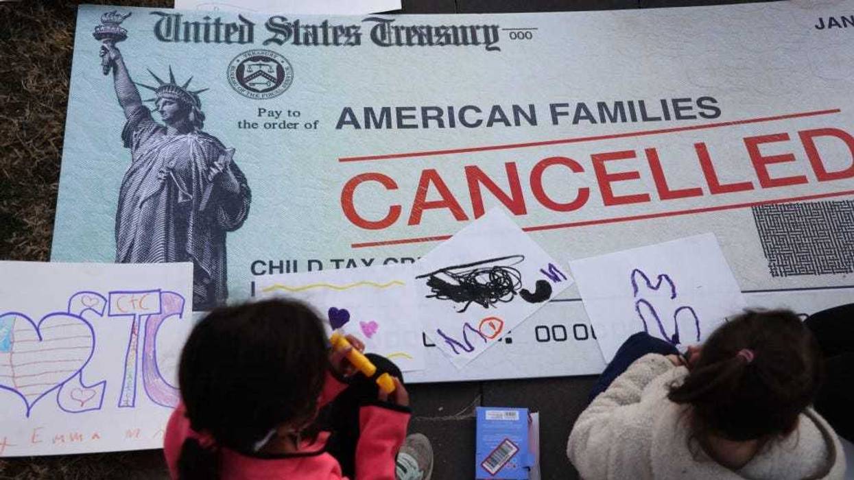 Children draw on top of a 'cancelled check' prop during a rally in front of the U.S. Capitol December 13, 2021 in Washington, DC.