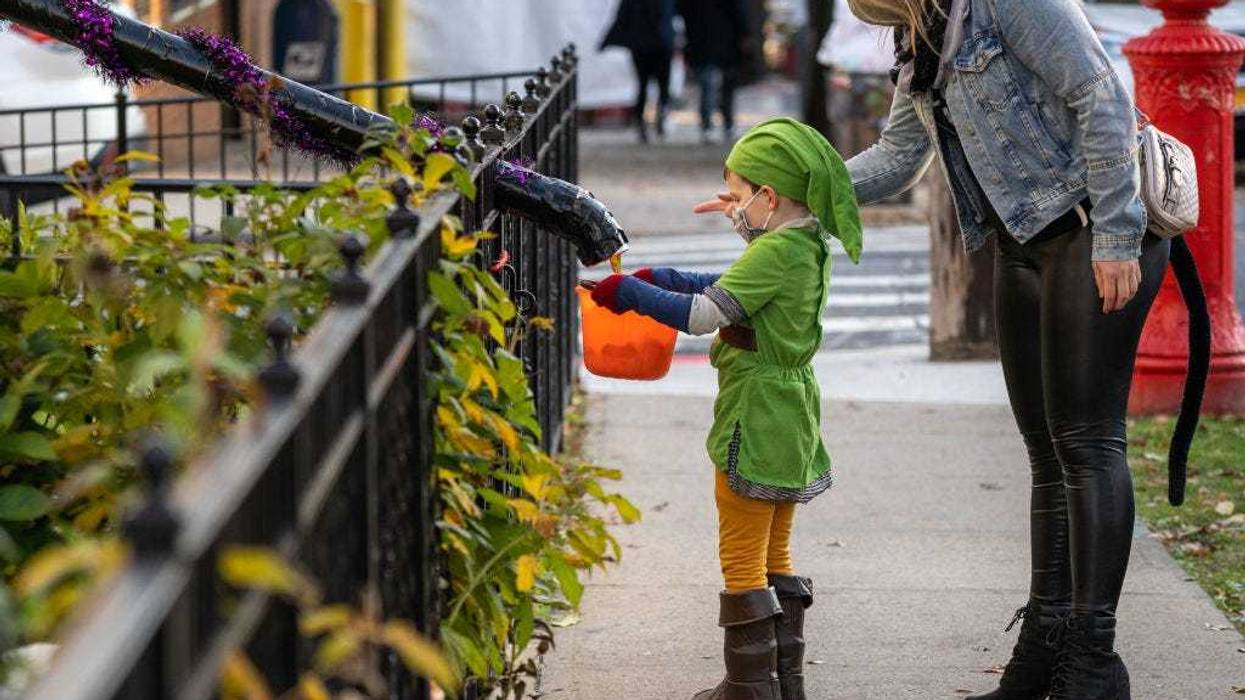 Children receive treats by candy chutes while trick-or-treating for Halloween in Woodlawn Heights on October 31, 2020 in New York City. The CDC shared on their website alternative ways to still celebrate the holiday while being safe.