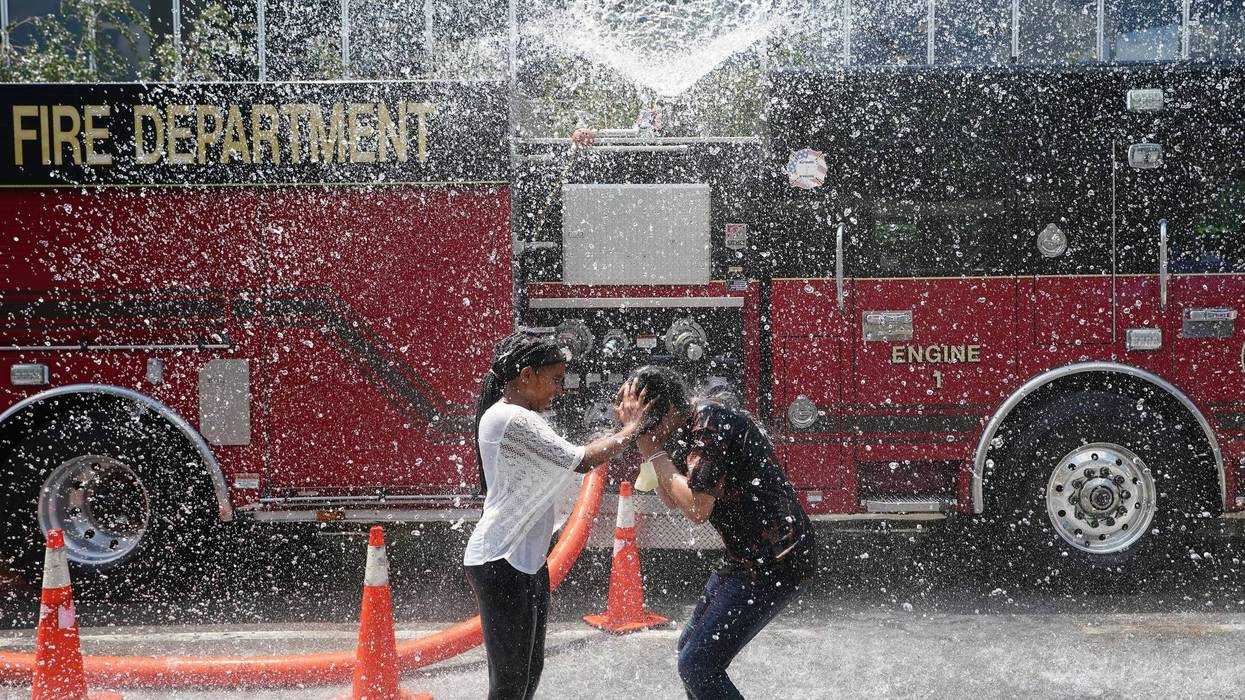 Children try to beat the 98 degree heat by running through a water spray provided by the St. Louis Fire Department on Day 2 of the Fair St. Louis in St. Louis on Monday, July 4, 2022.