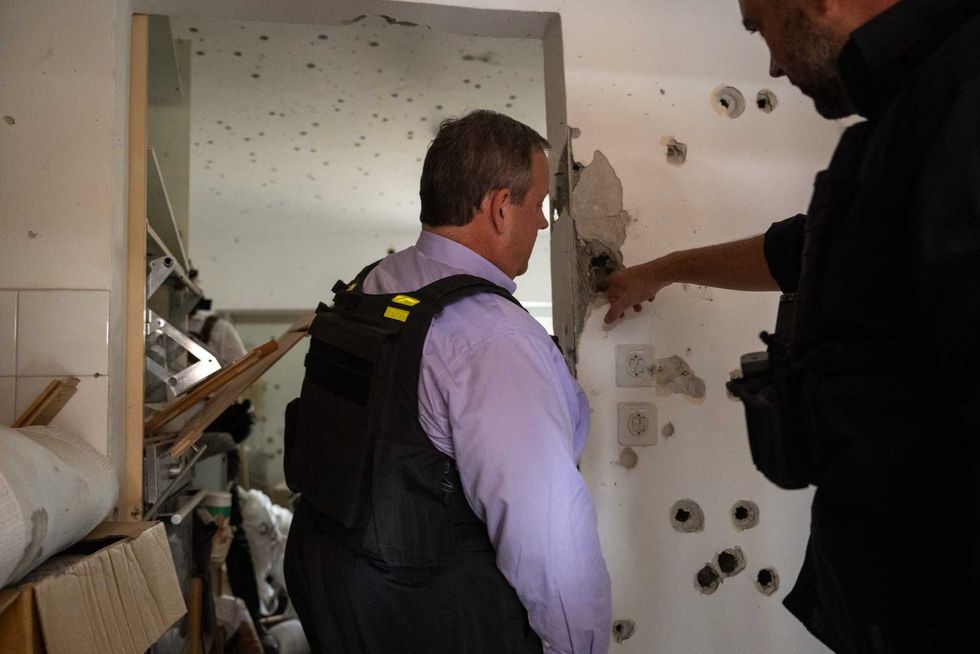 Chris Christie looks at a wall in a home riddled with bullet holes at Kibbutz Kfar Aza