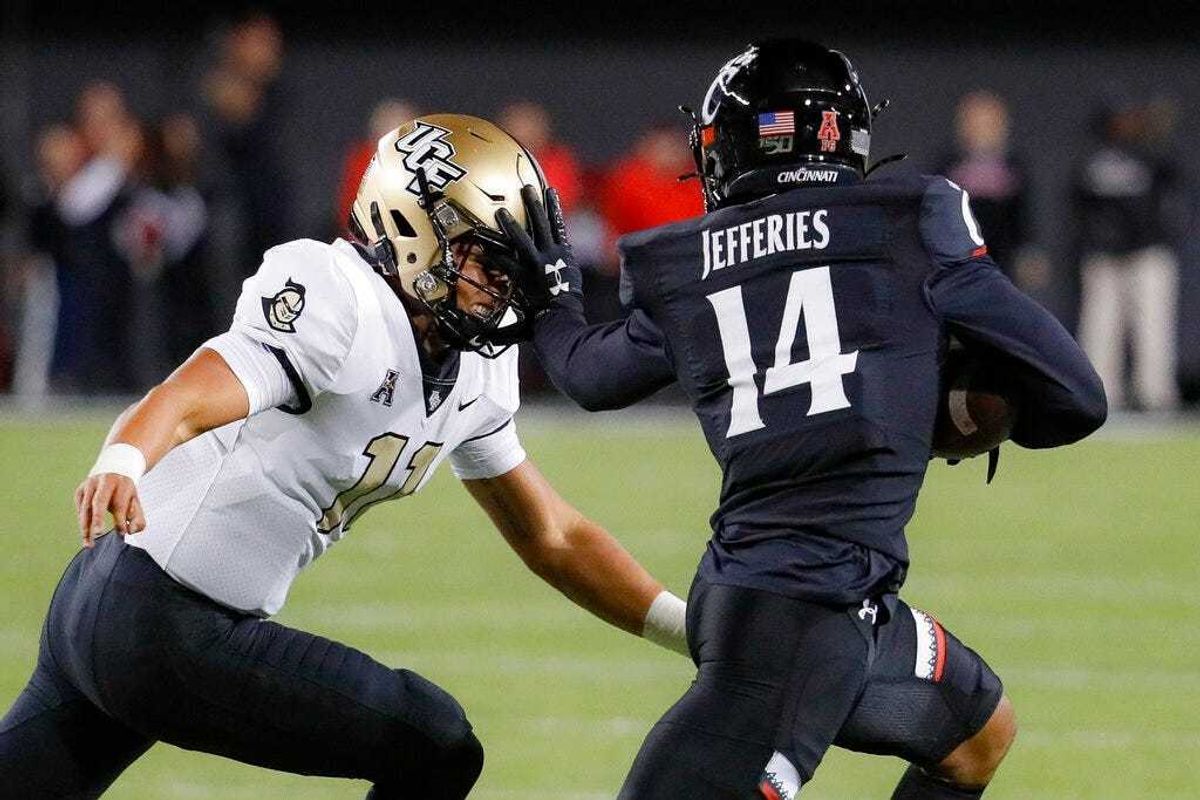 Cincinnati cornerback Cam Jefferies (14) stiff-arms UCF quarterback Dillon Gabriel (11) after intercepting a pass during the first half of an NCAA college football game Friday, Oct. 4, 2019, in Cincinnati.