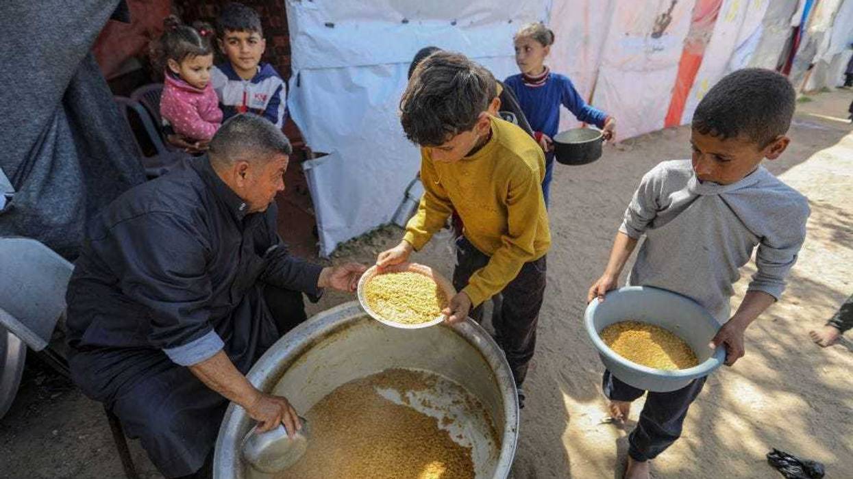 Citizens queue for food that is cooked in large pots and distributed for free during war-time on March 10, 2024 in Rafah, Gaza.
