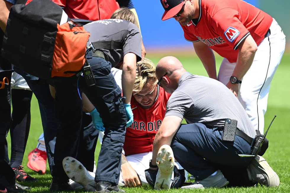 Cleveland Guardians shortstop Gabriel Arias (13) is looked at by medical personnel and manager Stephen Vogt (12) after suffering an injury trying to field a ground ball hit by St. Louis Cardinals shortstop Masyn Winn (not pictured) during the third inning at Progressive Field.