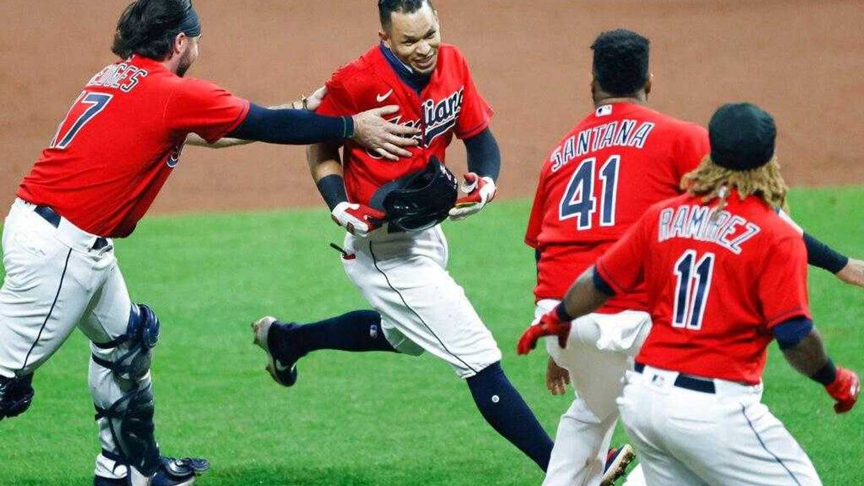Cleveland Indians' Cesar Hernandez, center, is mobbed by Austin Hedges (17), Carlos Santana (41) and Jose Ramirez (11) after hitting a winning single off Pittsburgh Pirates relief pitcher Chris Stratton during the ninth inning of a baseball game, Friday, Sept. 25, 2020, in Cleveland.