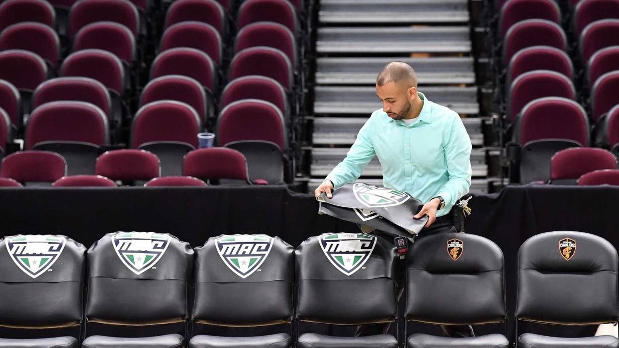 Cleveland, Ohio, USA; A worker removes the insignia of the Mid-American Conference from the bench chairs at Rocket Mortgage FieldHouse. The game between the Akron Zips and the Ohio Bobcats and the Mid-American Conference basketball tournament as a whole was cancelled in an attempt to prevent the spread of the Covid-19 coronavirus.