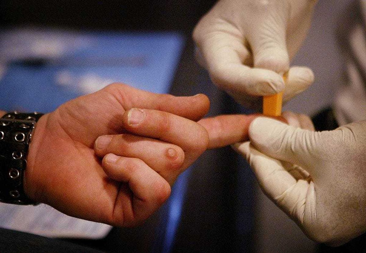 Cliff Sanchez (R), a phlebotomist with the Chicago Recovery Alliance (CRA), questions an intravenous drug user before testing him for HIV antibodies inside one of the organizations mobile outreach vans May 10, 2006 in Cicero, Illinois.
