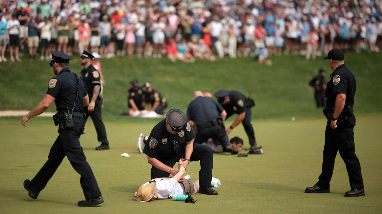 Climate change protestors are ushered off the 18th green by police officers during the final round of the Travelers Championship at TPC River Highlands on June 23, 2024 in Cromwell.