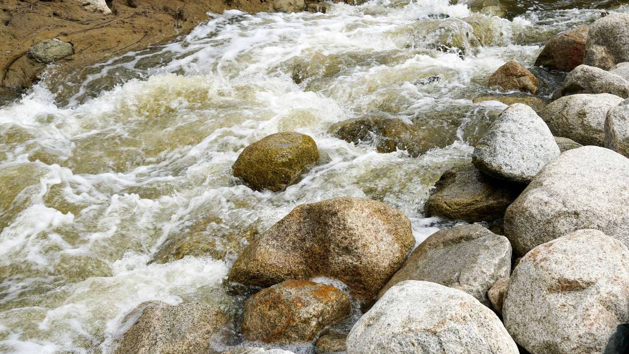 Close up fast flowing water between rocks in the mountain river,
