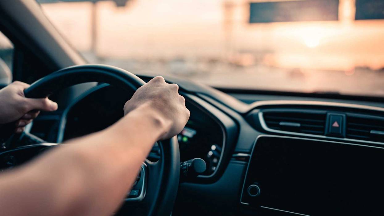 Close-up - Hand of man driving car on the road.